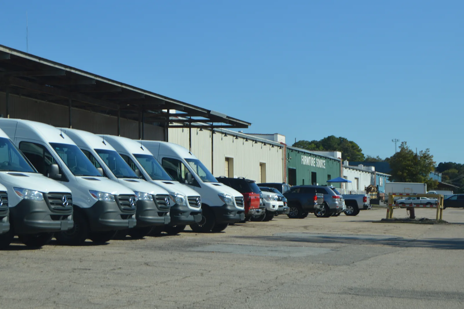 Light industrial warehouse with vans parked along the front.